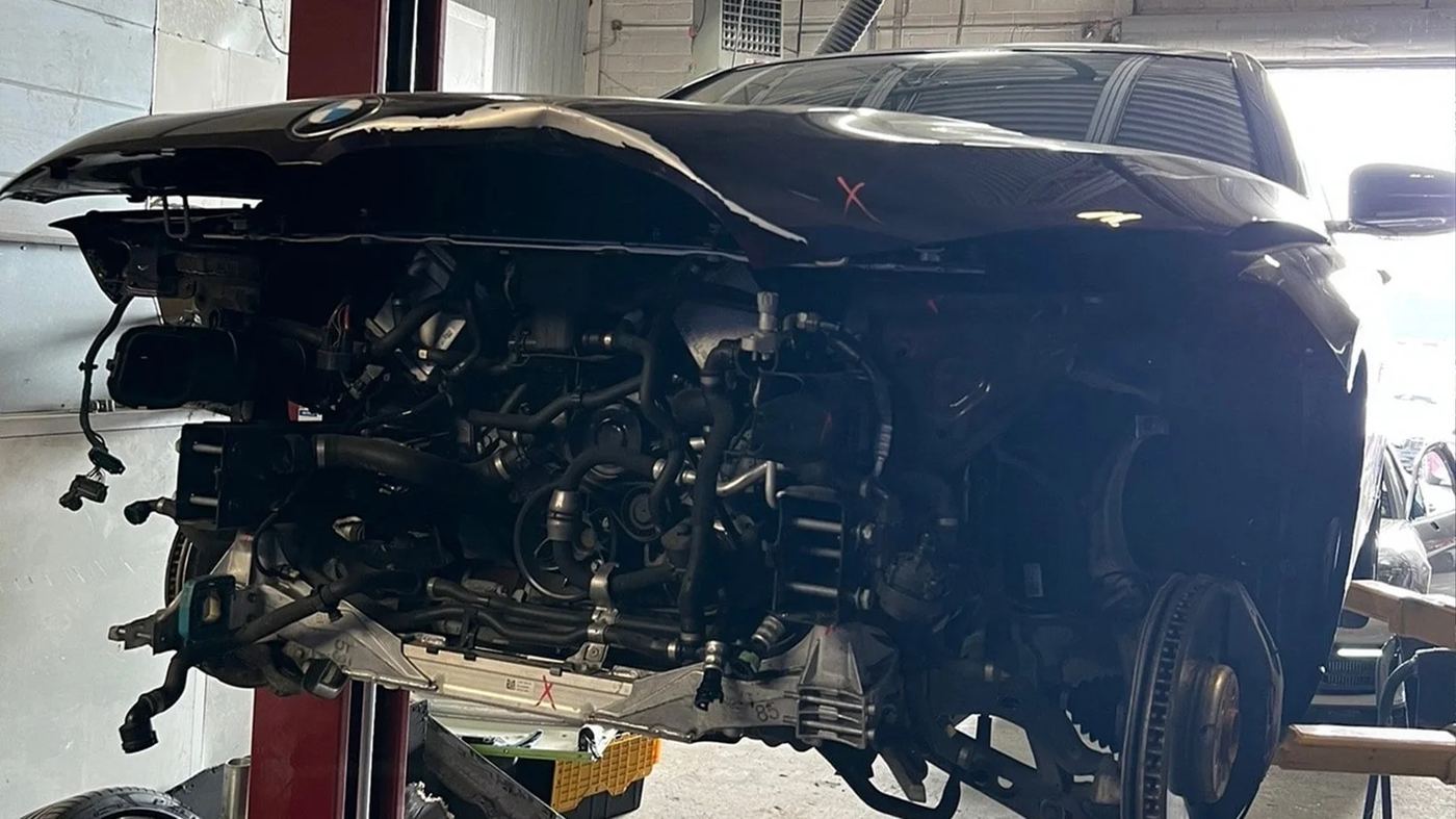 A BMW with its front end stripped down inside the Always Towing & Collision shop